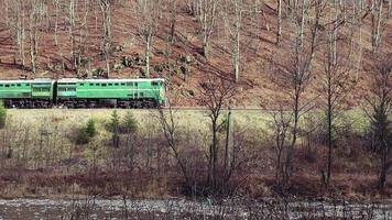 um velho trem monta fumaça nos trilhos para as montanhas no outono em um dia nublado. passeios de trem de passageiros pela floresta. video