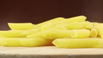 langsam drehende rohe Penne Rigate ist eine kurze Pasta mit schrägen Schnitten und einer gerippten Oberfläche. traditionelle italienische Pasta. bleibt nicht hängen. Nahaufnahme Seitenansicht. video