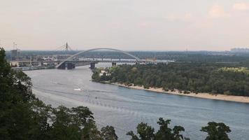 een mooi visie van de historisch een deel van de stad van kiev en de dnjepr van de glas voetganger brug, achtergrond. genoegen boten Aan de dnjepr. panorama van kiev van de lucht. video