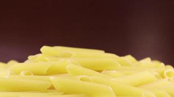 langsam drehende rohe Penne Rigate ist eine kurze Pasta mit schrägen Schnitten und einer gerippten Oberfläche. traditionelle italienische Pasta. bleibt nicht hängen. Nahaufnahme Seitenansicht. video