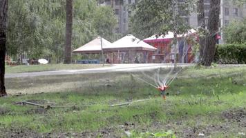 Rasenbewässerungssystem, das in einem grünen Park arbeitet. Besprühen Sie den Rasen bei heißem Wetter mit Wasser. automatischer Sprinkler. der automatische Bewässerungssprinklerkopf bewässert den Rasen. intelligenter Garten. video