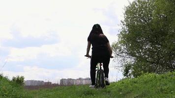 ciclista feminina irreconhecível joga uma garrafa de plástico na grama da floresta. deixa lixo e bicicletas fora. o conceito de problema ambiental, reciclagem de plástico, poluição da natureza. video