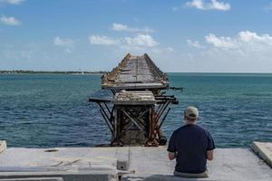 man flying a drone in damaged bridge in key west island photo