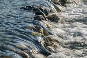 flujo del río al atardecer detalle del agua en las rocas de cerca foto