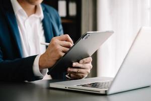 mano de hombre de negocios usando un teléfono inteligente, pagos de tabletas, compras en línea, canal omni, computadora de teclado de acoplamiento de tableta digital en la oficina foto