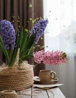 una canasta de jacintos y un par de té en una mesa junto a la ventana. naturaleza muerta de primavera foto