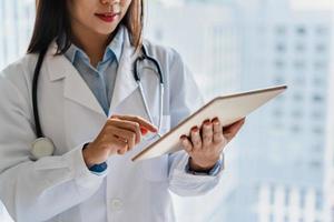 Female doctor working on smart device in the medical office at the hospital photo