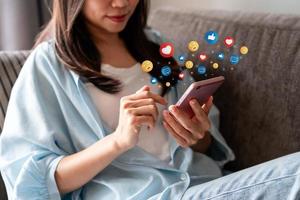 Young woman using mobile phone and relaxing at home, Modern lifestyle and social media concept. photo