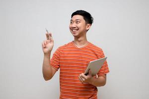 Un hombre de negocios asiático positivo con camisa a rayas sostiene un gesto de tableta comprobando el trabajo aislado foto