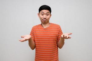 Positive asian man striped shirt handsome show hands up about I dont know isolated photo