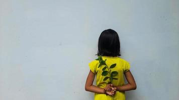 Little girl holding young plant.  Green Leaves. Ecology concept. Light color background. photo