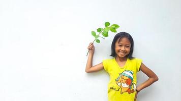 Little girl holding young plant.  Green Leaves. Ecology concept. Light color background. photo