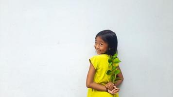 Little girl holding young plant.  Green Leaves. Ecology concept. Light color background. photo