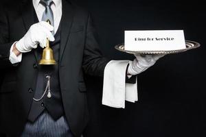 Portrait of Butler in Dark Suit Holding Tray and Bell. Ring for Service. Concept of Service Industry and Professional Hospitality. photo
