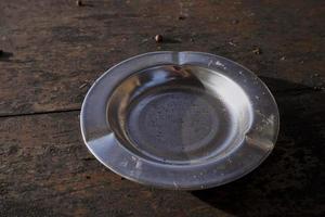 Close up of stainless ashtray against a wooden brown background. Copy space. photo