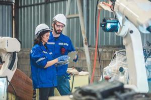 Engineers team mechanic using computer controller Robotic arm for welding steel in steel factory workshop. Industry robot programming software for automated manufacturing technology photo