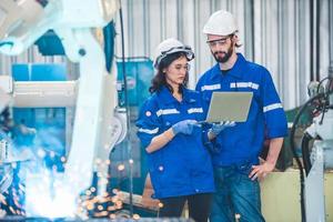 Engineers team mechanic using computer controller Robotic arm for welding steel in steel factory workshop. Industry robot programming software for automated manufacturing technology photo