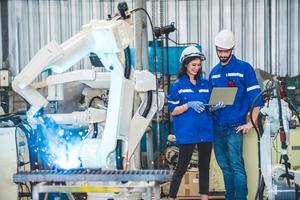 Engineers team mechanic using computer controller Robotic arm for welding steel in steel factory workshop. Industry robot programming software for automated manufacturing technology photo