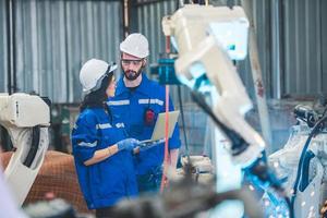 Engineers team mechanic using computer controller Robotic arm for welding steel in steel factory workshop. Industry robot programming software for automated manufacturing technology photo