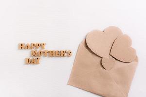 Happy mother's day. Wooden letters and cardboard hearts in an envelope on a light background. photo