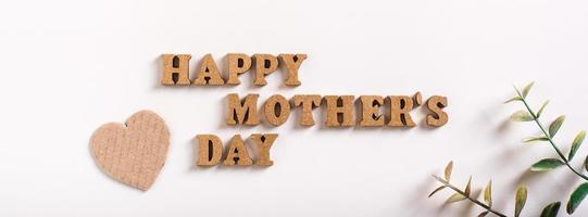 feliz día de la madre. letras de madera, corazones de cartón y ramas de eucalipto. banner web foto