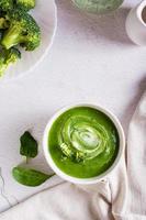 Bowl with broccoli cream soup on the table. Healthy food. Top and vertical view photo