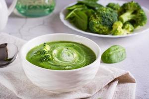 Fresh broccoli puree soup in a bowl on the table. Vegetarian food. photo