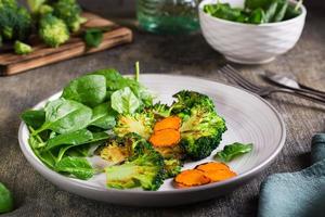 Fried broccoli, carrots and spinach leaves on a plate. Healthy food.