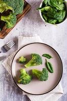 hojas frescas de brócoli y espinacas en un plato sobre la mesa. comida sana, comida verde. vista superior y vertical