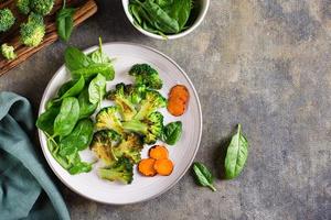 brócoli frito, zanahorias y hojas de espinacas en un plato. comida sana. vista superior foto