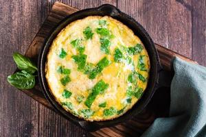 Omelet with spinach and cheese in a pan on the table. Ketogenic diet. Top view. Closeup photo