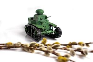 Model of an old Soviet tank made of paper on a white background. Willow branch in the foreground. photo