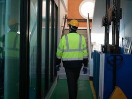 Backside person labor engineer staff yellow hardhat safety stand walk check up report factory forklift construction inspector industry company manufacturing  technician machinery control production photo