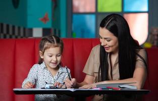 Mother helping her daughter with homework. Mother helping her daughter with homework. Happy childhood photo