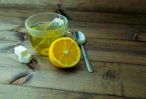 Green tea with lemon in a mug, sugar and a spoon. photo