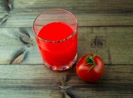 jugo de tomate y tomate en una mesa de madera oscura. foto