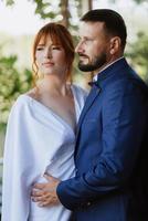 bride in a white dress with a bouquet and the groom in a blue suit photo