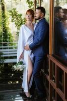 bride in a white dress with a bouquet and the groom in a blue suit photo