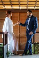 bride in a white dress with a bouquet and the groom in a blue suit photo