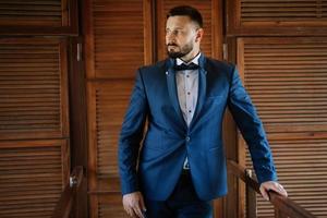 portrait of a groom with a beard in a blue suit photo