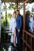 bride in a white dress with a bouquet and the groom in a blue suit photo