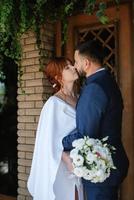 novia con un vestido blanco con un ramo y el novio con un traje azul foto