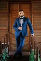 retrato de un novio con barba en un traje azul foto