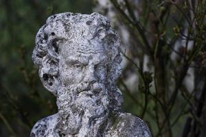 Old faun sculpture on forest background photo