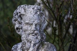 antigua escultura de fauno en el fondo del bosque foto