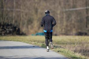 man while jogging on country road photo