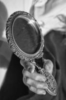 mano de mujer sosteniendo un espejo en blanco y negro foto