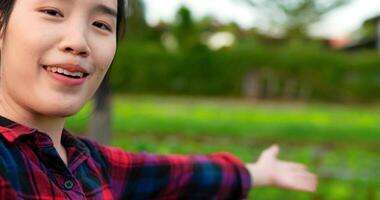 Handheld close-up shot, Woman farmer Wear plaid shirt talking on smartphone to video streaming review her organic vegetable farm, smile with happy, Smart farmer with technology device concept