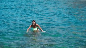 una joven alegre nada en la salvaje playa rocosa video
