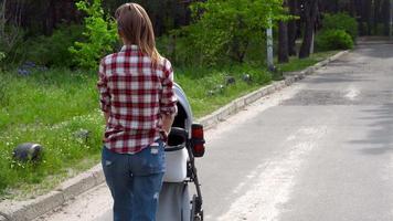 una joven madre camina con un bebé en un cochecito